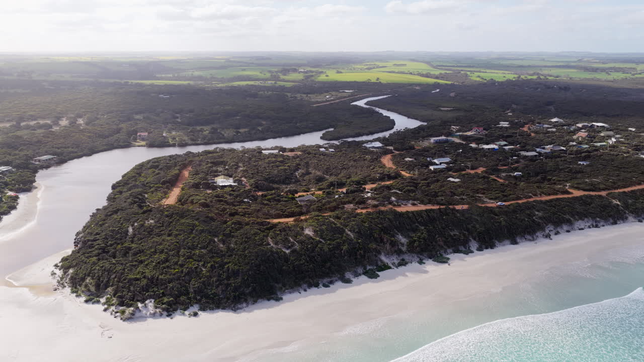 Et bredt gyldent øjeblik over de hvide sandstrande og Vivonne Bay-floden, med røde grusveje og bølgende grønne bakker i det frodige kystlandskab på Kangaroo Island, Australien i det fjerne