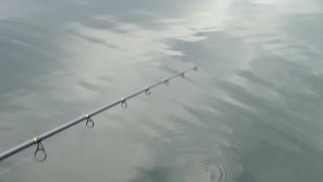 Fishing-Rod-Over-Calm-Pond-Water-At-Daytime