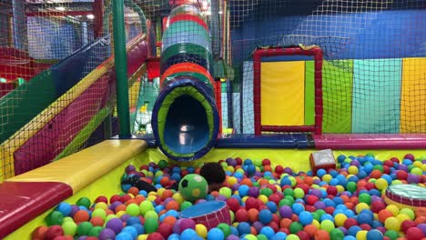 exótico y lindo bebé de dos años divirtiéndose en la piscina de bolas dentro de un parque infantil