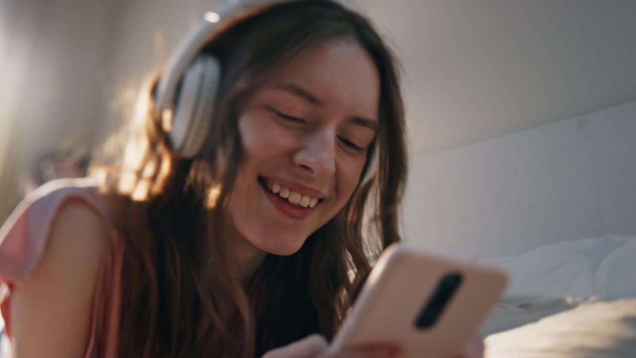 Ragazza felice che si gode la musica in cuffia a casa in primo piano. Donna gioiosa che usa il cellulare.