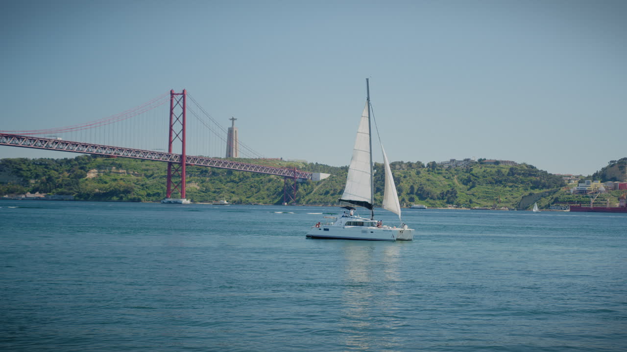 puente del 25 de abril en belem lisboa barco de vela que pasa por el tiro largo