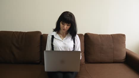 young woman using laptop at home sitting on sofa