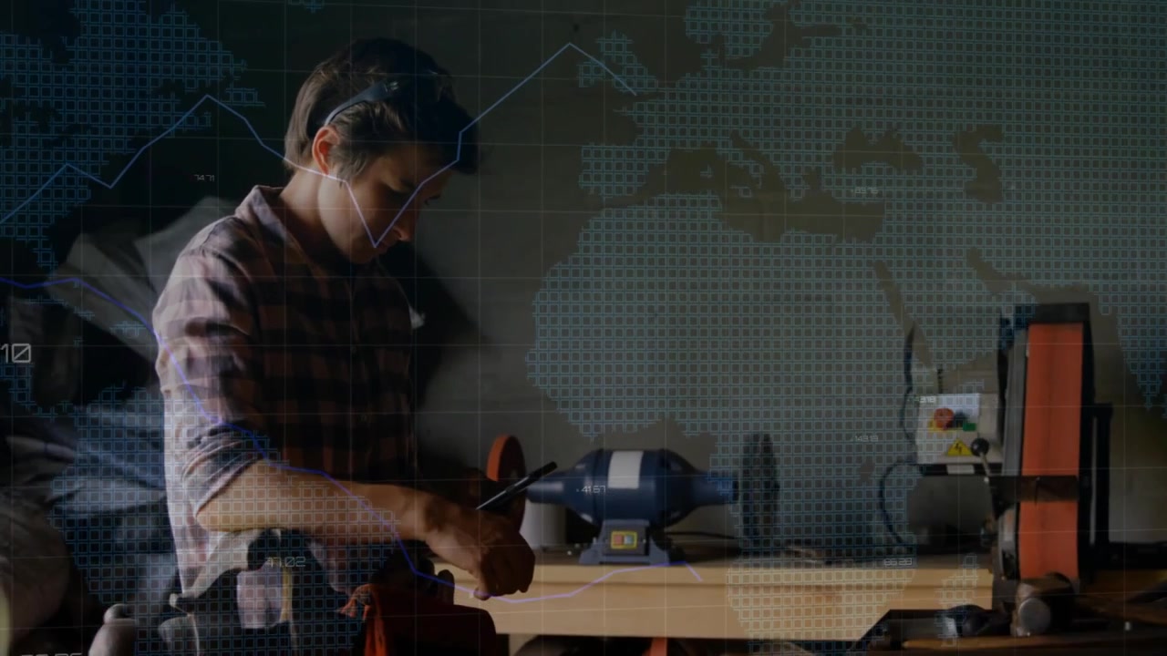 Man adjusting tool in technology workshop, overlaying digital grid map and fluctuating line graphs