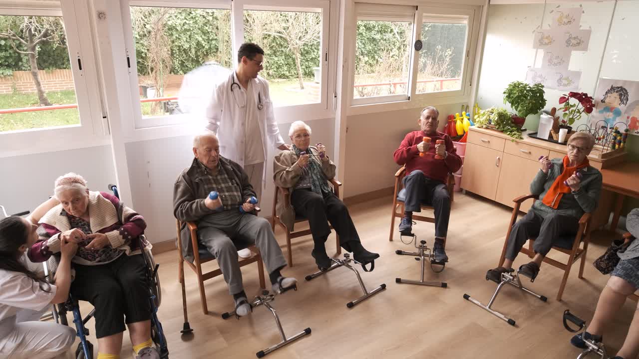 Friendly caregivers assisting senior people in pedal exercise and weightlifting at nursing home