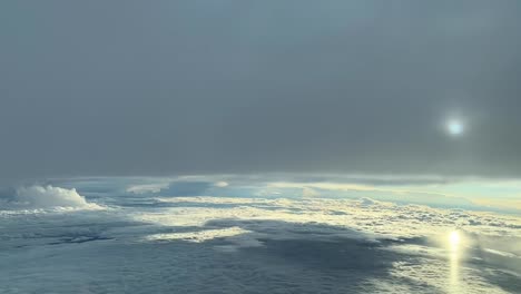 aerial view taken from a jet cockpit flying between layers of cluds with a hidden sun and reflections