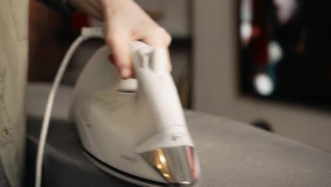 Woman-is-ironing-a-table-cloth-with-an-electric-iron-at-home,-domestic-household-maintenance-concept