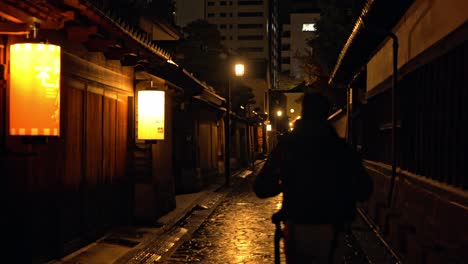 a man walks alone through the atmospheric streets of kanazawa's historic district at night.