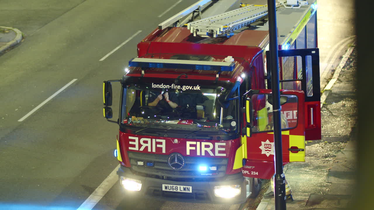 A firefighter gets into a fire engine in London at night, England