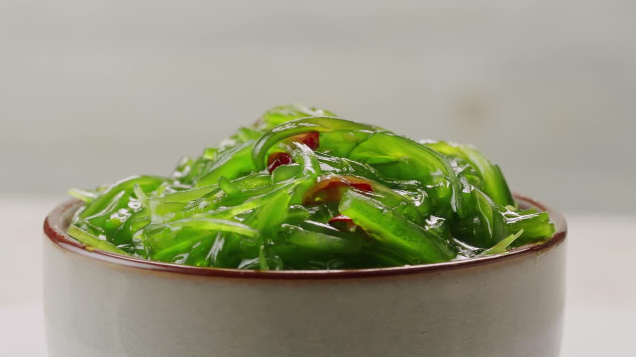 Japanese wakame chuka fermented food. Close-up on a detail of Hiyashi Wakame Chuka or seaweed salad or seaweed with sesame seeds on a plate. Top view. Seafood background. Health concept.
