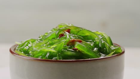 japanese wakame chuka fermented food. close-up on a detail of hiyashi wakame chuka or seaweed salad or seaweed with sesame seeds on a plate. top view. seafood background. health concept.