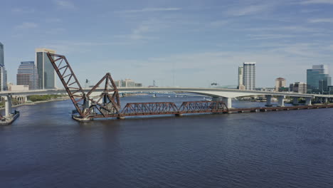 jacksonville florida aerial v8 pan left shot of railroad bridge, highway bridge and traffic during rush hour - march 2020