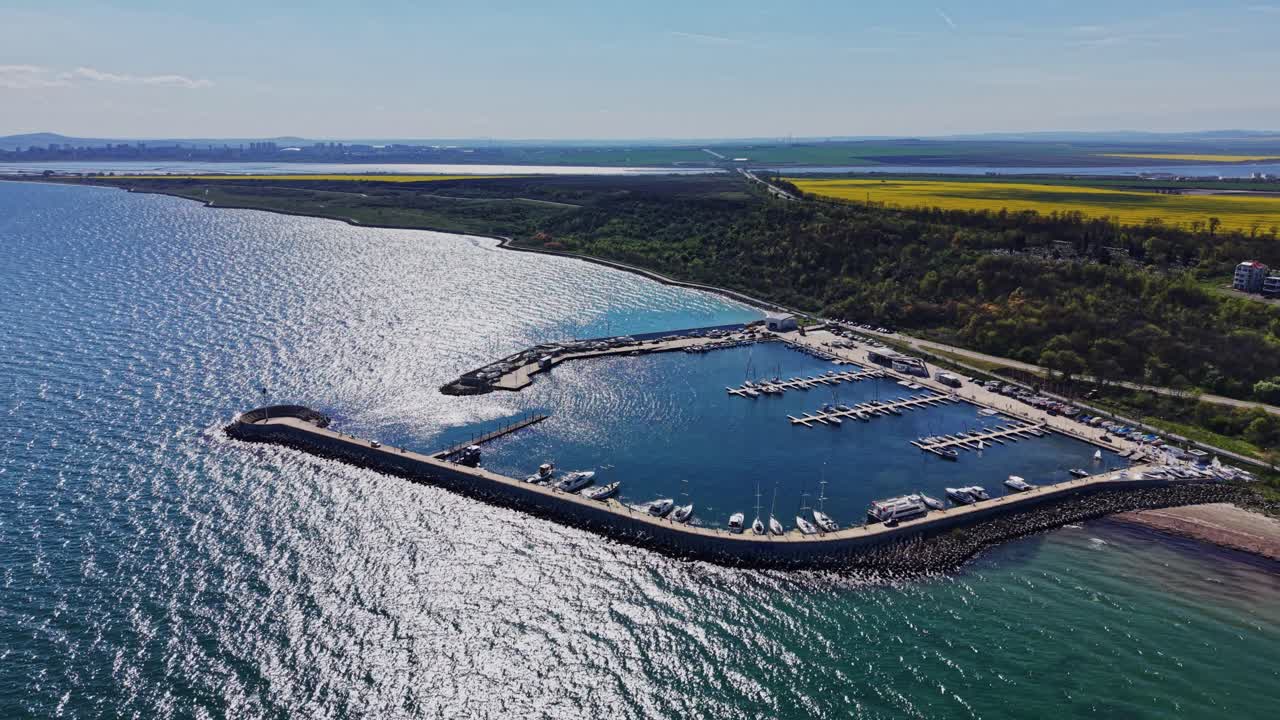 Marina lungo la costa con barche vicino a una zona rurale e acqua blu.