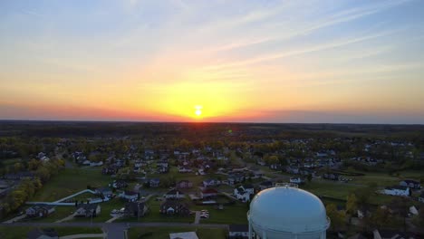 hermosa puesta de sol aérea sobre el barrio suburbano con torre de agua en primer plano