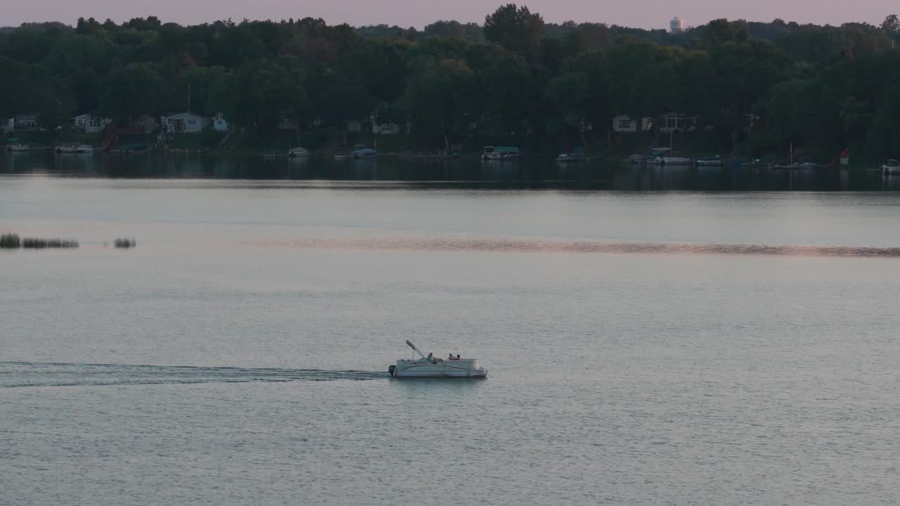 Telephoto aerial dolly shot of a pontoon boat on North Center Lake at sunset in Minnesota. 4K