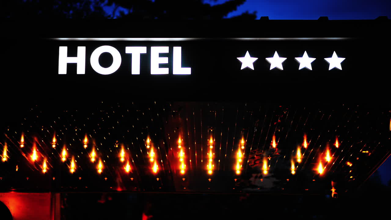 White neon 4 star hotel sign with orange lights, at night