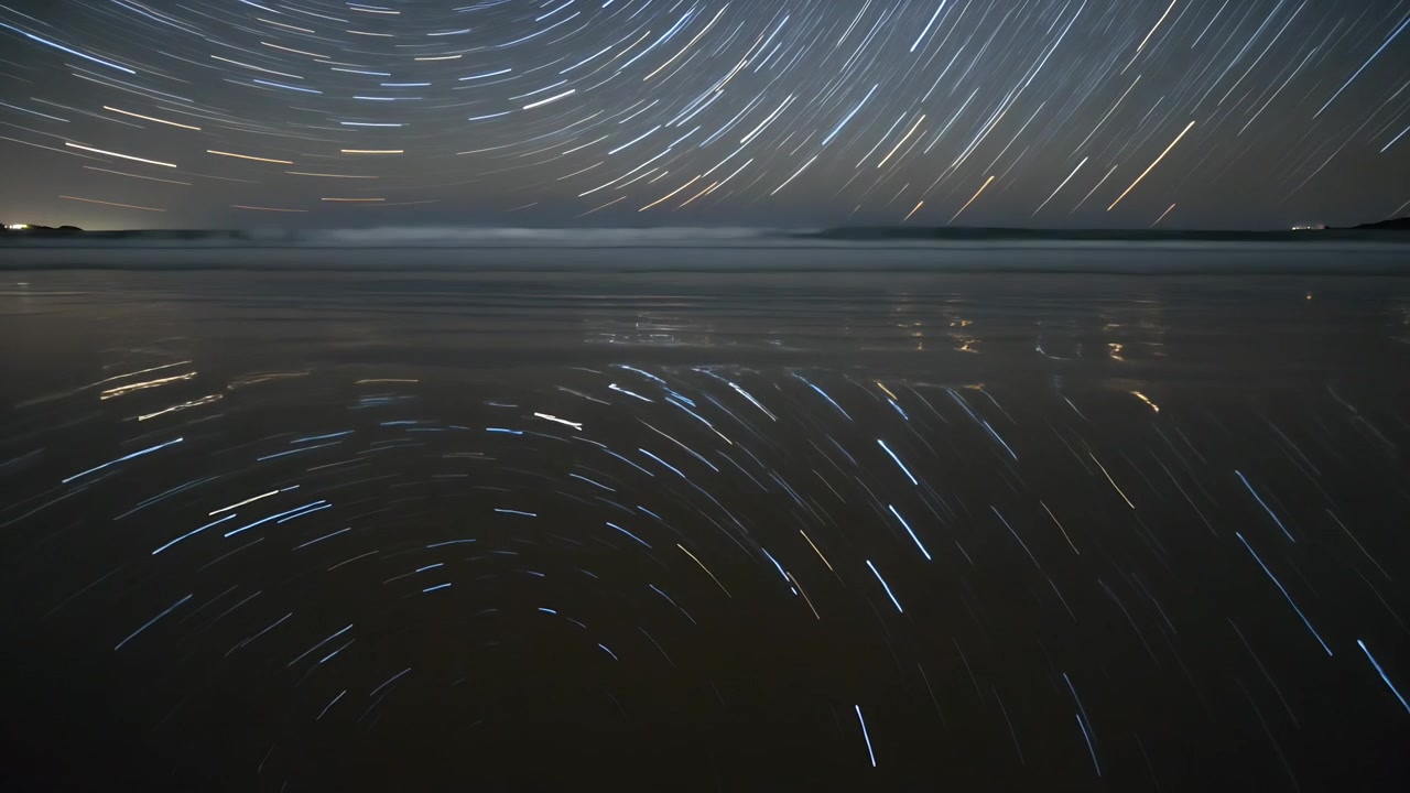 Kamera merekam jejak bintang yang berputar menyapu di pantai, memantulkan pasir basah untuk timelapse.