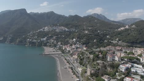 slow reveal ariel toma de una hermosa playa de arena con altas y altas montañas en el fondo en una pequeña y turística ciudad en el corazón de italia