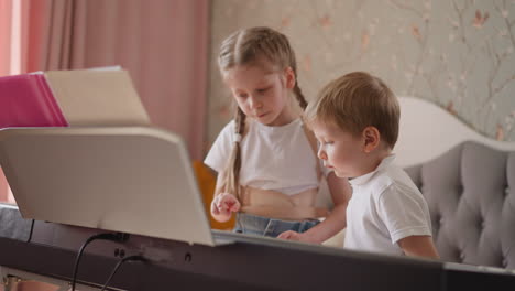 elder girl shows simple musical exercise to little brother