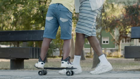 Padre-Sosteniendo-La-Mano-De-Su-Hijo-Ayudando-A-Andar-En-Patineta.