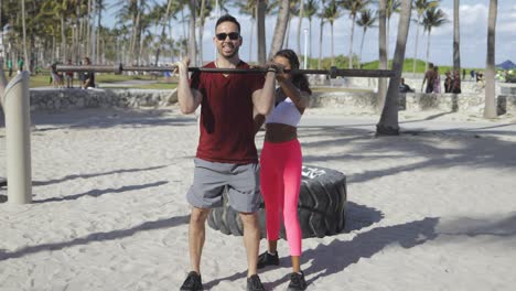 Frau-Hilft-Mann-Beim-Training-Am-Strand