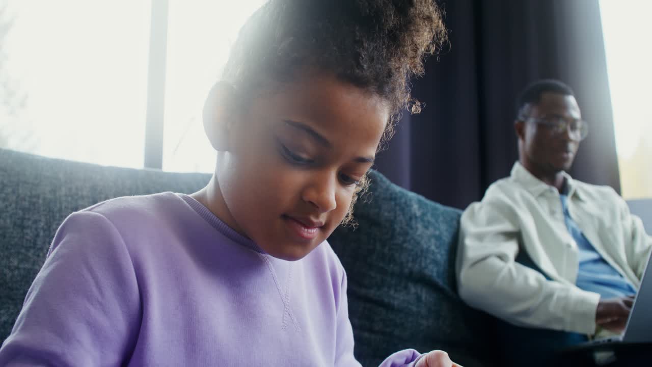 Child playing video games while father uses laptop