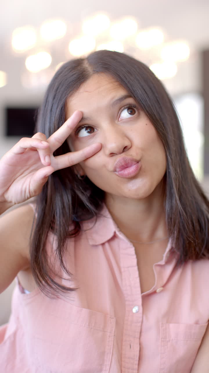 Vertical video: Smiling teenage girl making peace sign gesture, enjoying time with friends
