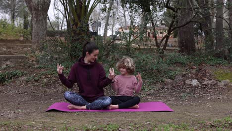 mother with son meditating on yoga mat in park