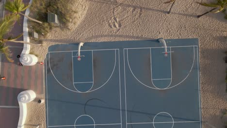 a nose down drone shot over a basketball court at the beach