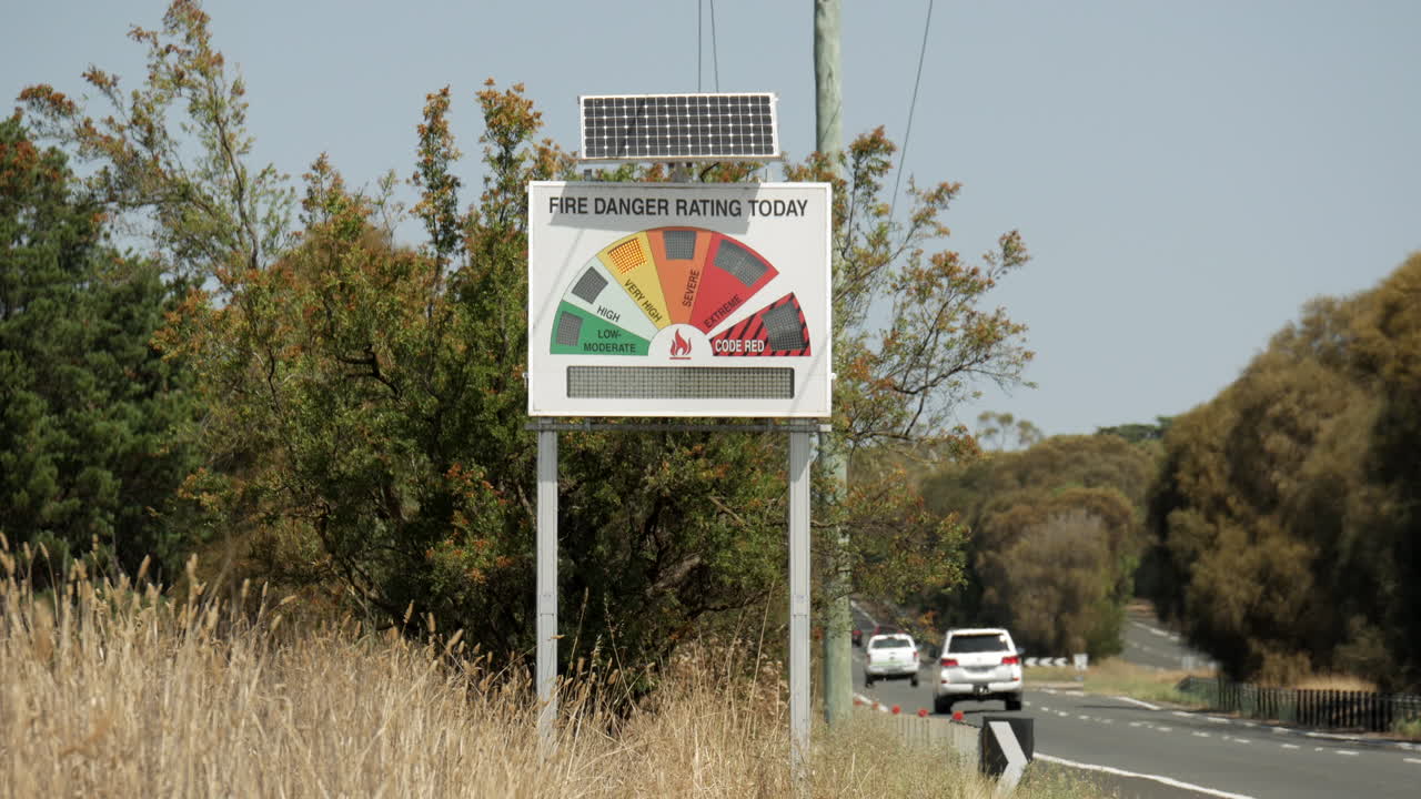 Fire danger alert signal along an Australian highway. The sign indicates the level of danger during the summer bush fire season. Shimmering heat waves visible in the footage. LOCKED DOWN SHOT.