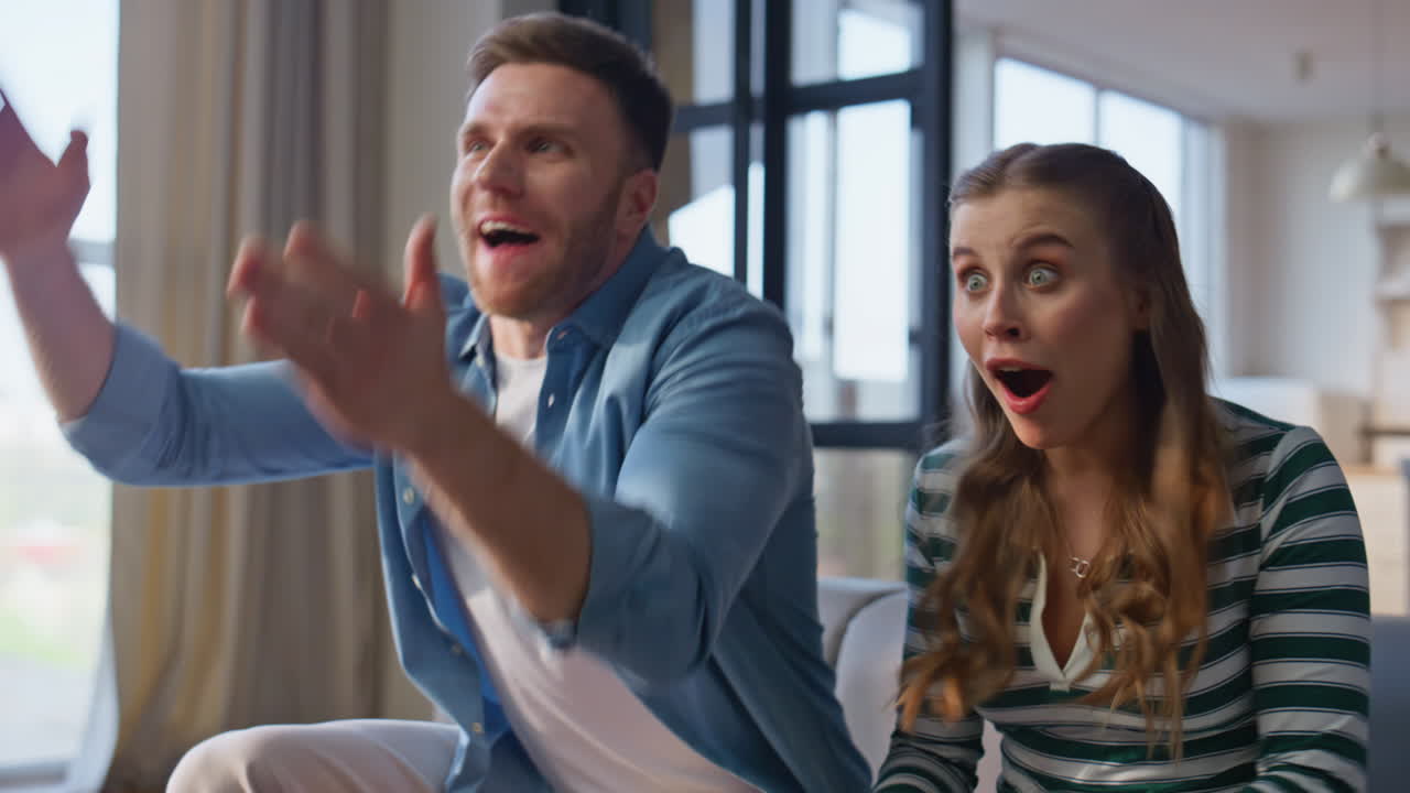 Excited spouses supporting soccer watching television closeup. Euphoric couple