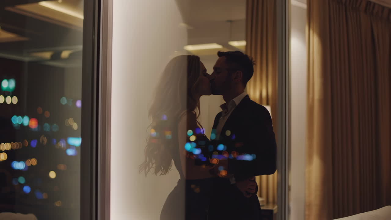 Romantic Couple Kissing in Luxury Apartment with City View at Night