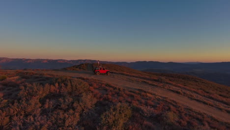 joven en la parte superior del techo jeep bailando en el impresionante paisaje del desierto de montaña