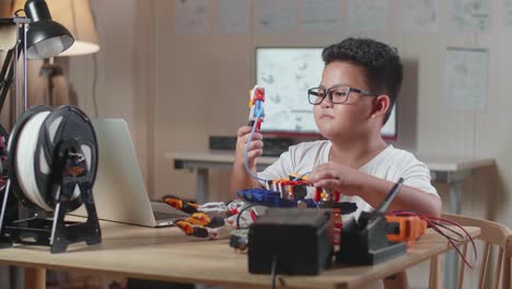 asian cute boy with a laptop checking a cyborg hand at home