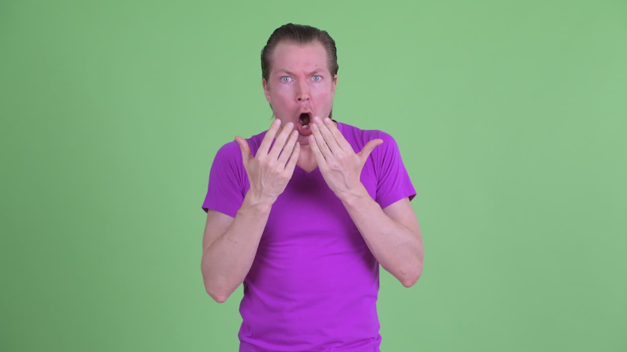 녹색 배경 에 충격 과 놀라움 을 느끼는 젊은 남자 의 스튜디오 촬영