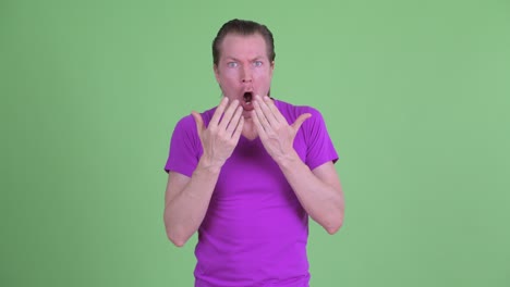 fotografía de estudio de un joven con aspecto conmocionado y sorprendido contra un fondo verde