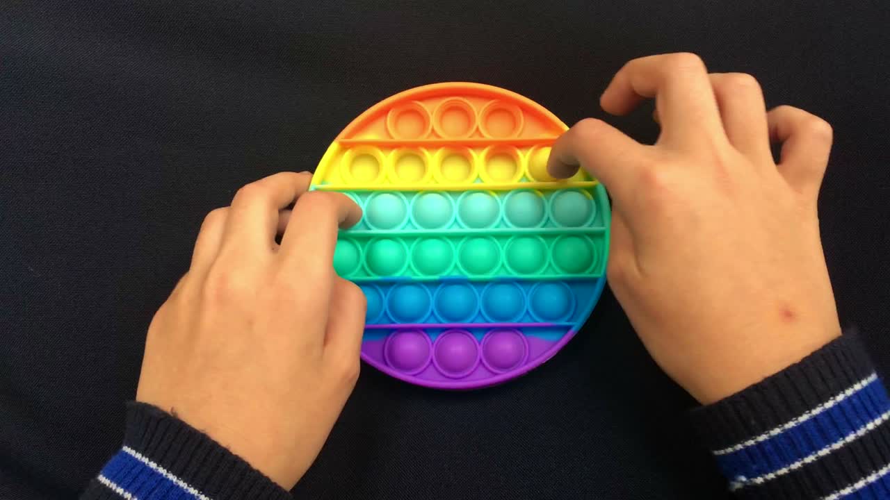 어린 아이가 푸시 팝을 가지고 놀고 거품 불안감 감각 장난감을 가지고 놀고 있습니다.