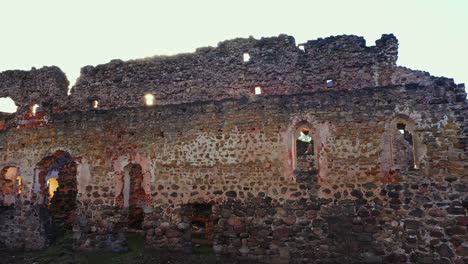 Parallax-shot-of-a-wall-of-Rauna-Castle-and-the-sun-shining-through-a-hole