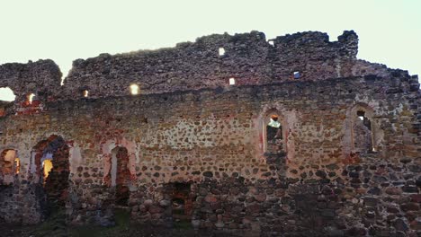 parallax shot of a wall of rauna castle and the sun shining through a hole