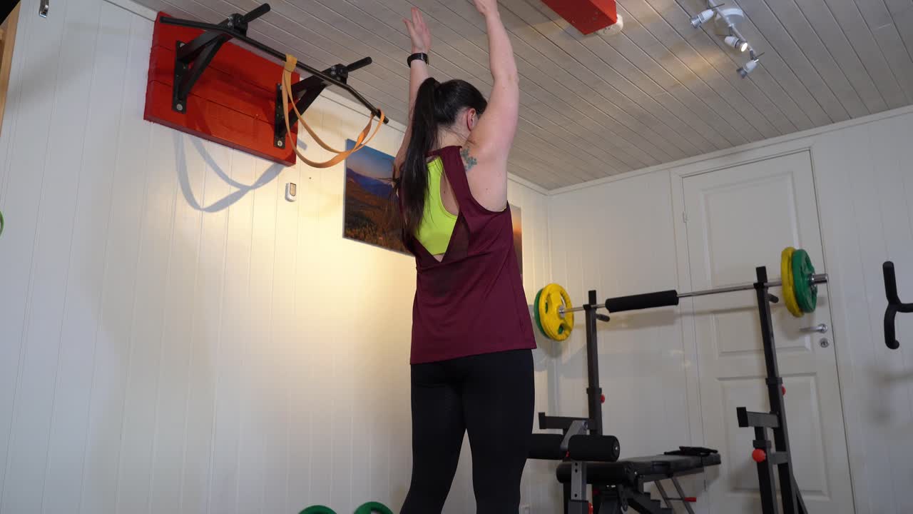 mujer de raza mixta calentándose antes del entrenamiento en casa - entrenamiento virtual ayudado por la aplicación telefónica