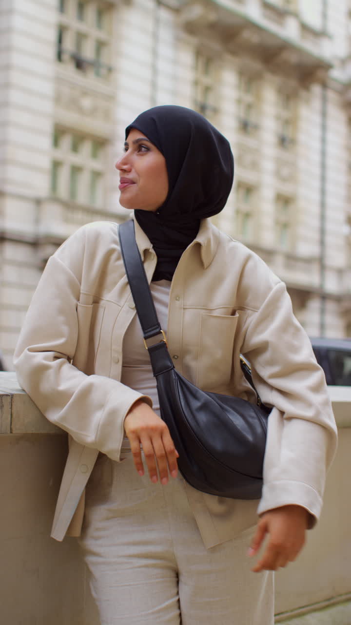 Vertical Video Portrait Of Smiling Muslim Businesswoman Wearing Hijab And Modern Business Suit Standing And Folding Arms Outside City Office Buildings 1