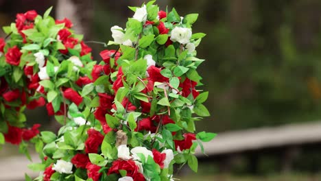 vibrant red and white artificial flowers gently sway in the breeze against a blurred natural background