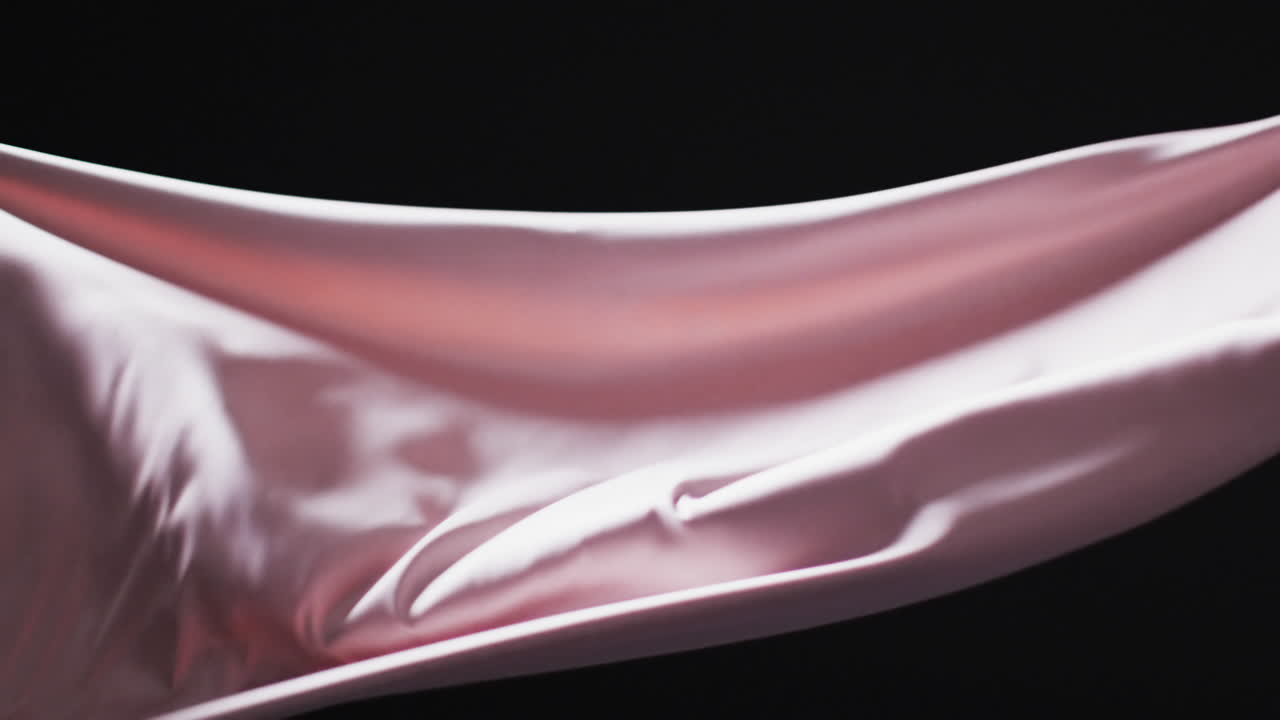 Animation of pink fabric blowing with copy space over black background