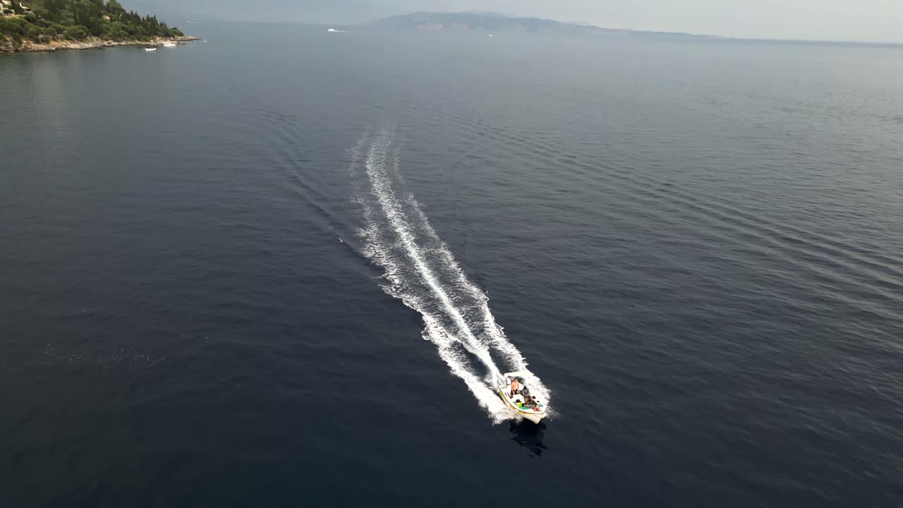 An aerial drone captures a dynamic shot of a boat cruising at high speed across the ocean, creating an exhilarating and dramatic scene.