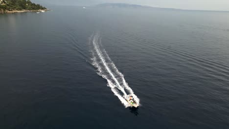 an aerial drone captures a dynamic shot of a boat cruising at high speed across the ocean, creating an exhilarating and dramatic scene.