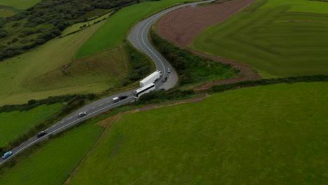 Hochwinkelansicht-Von-Fahrzeugen,-Die-Auf-Der-Straße-Auf-Dem-Land-Fahren.-Lkw-Fährt-In-Kurve-An-Bus-Vorbei.-Grüne-Wiesen-Und-Weiden.-Irland