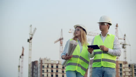 gerente de construcción e ingeniero caminan trabajando en el sitio de construcción usando tableta e impresión.