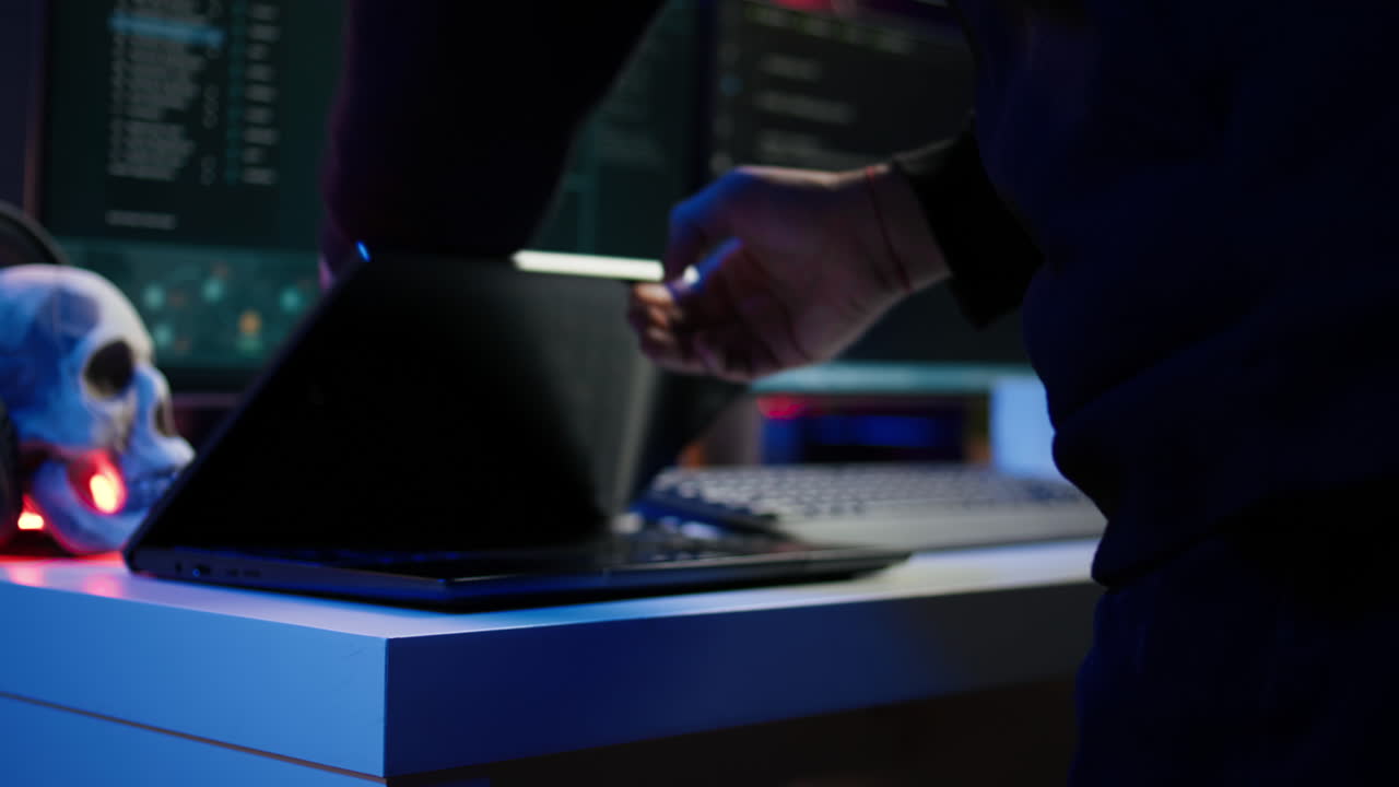 후드 해커가 가방에서 노트북을 꺼내서 ddos 공격을 준비하고 있습니다.