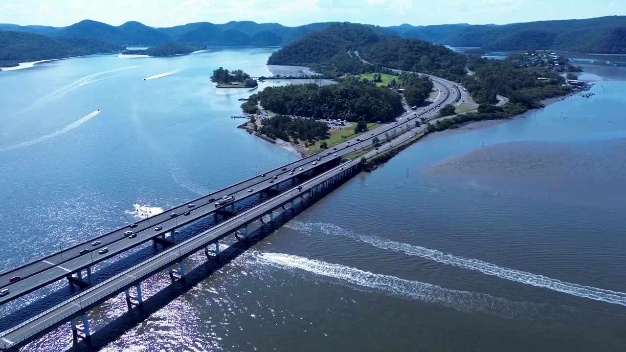 Luftfoto fra drone af biler og trafik, der kører langs motorvejen ved Brooklyn Bridge-vandvejene på Hawkesbury River med buskklædte bjerge i baggrunden, Hornsby Shire, NSW, Australien, turisme