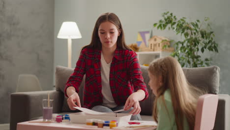 la hermana mayor cubre la bandeja con pintura para el arte ebru con la niña