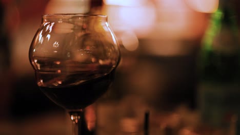 a wine glass with red wine in a dimly lit setting, creating a cozy and intimate atmosphere